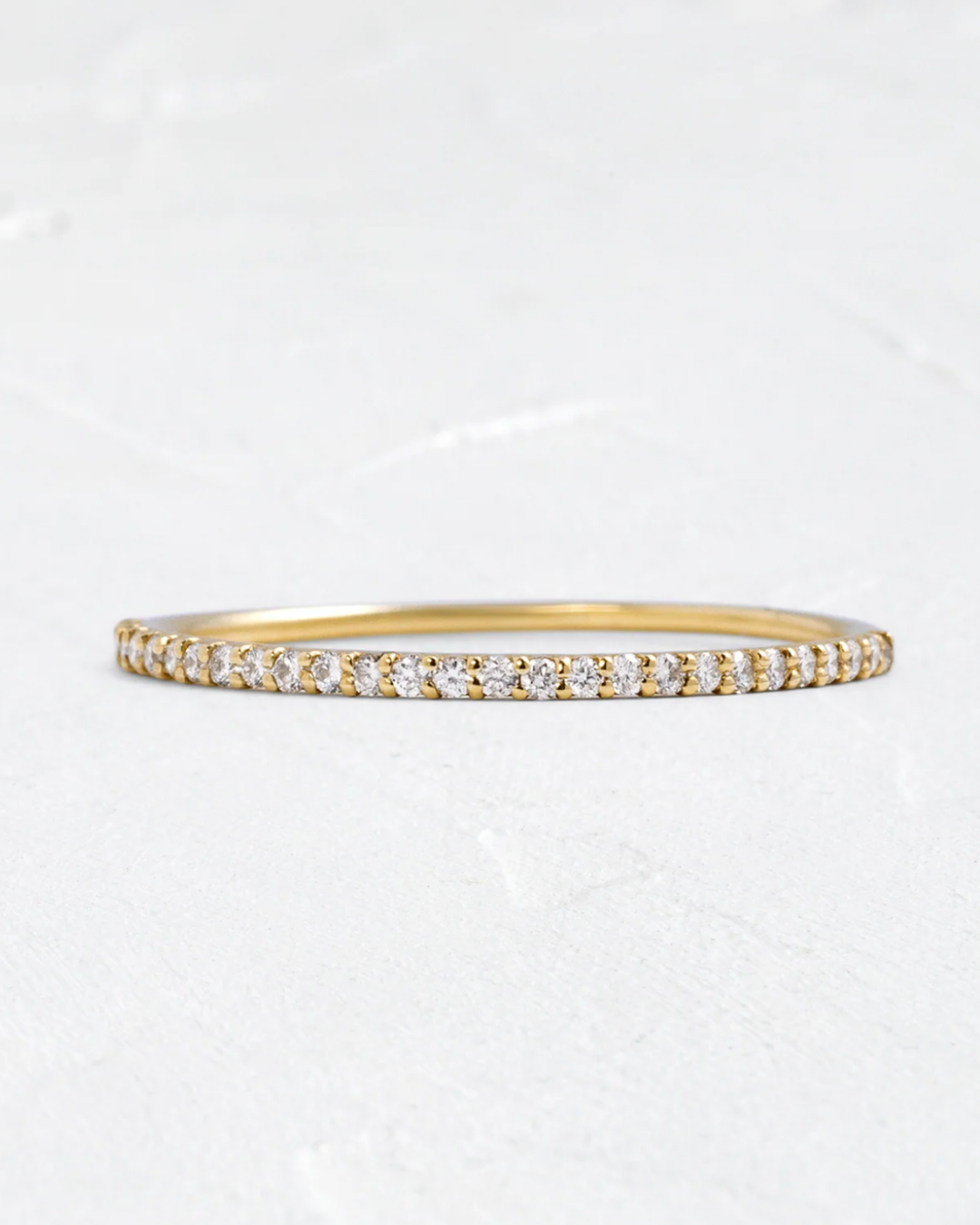 Gold bracelet with small diamonds on a light gray background