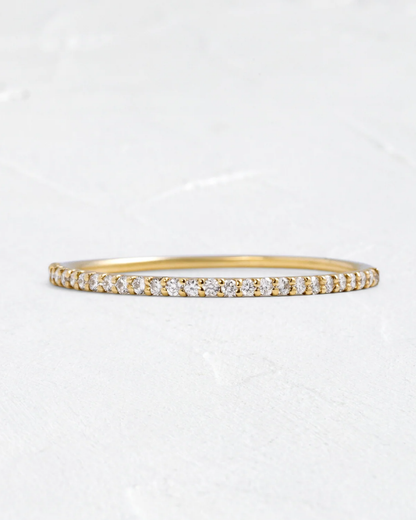 Gold bracelet with small diamonds on a light gray background